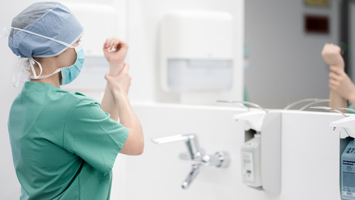 Eine Mitarbeiterin wäscht sich im OP-Bereich die Hände und Unterarme