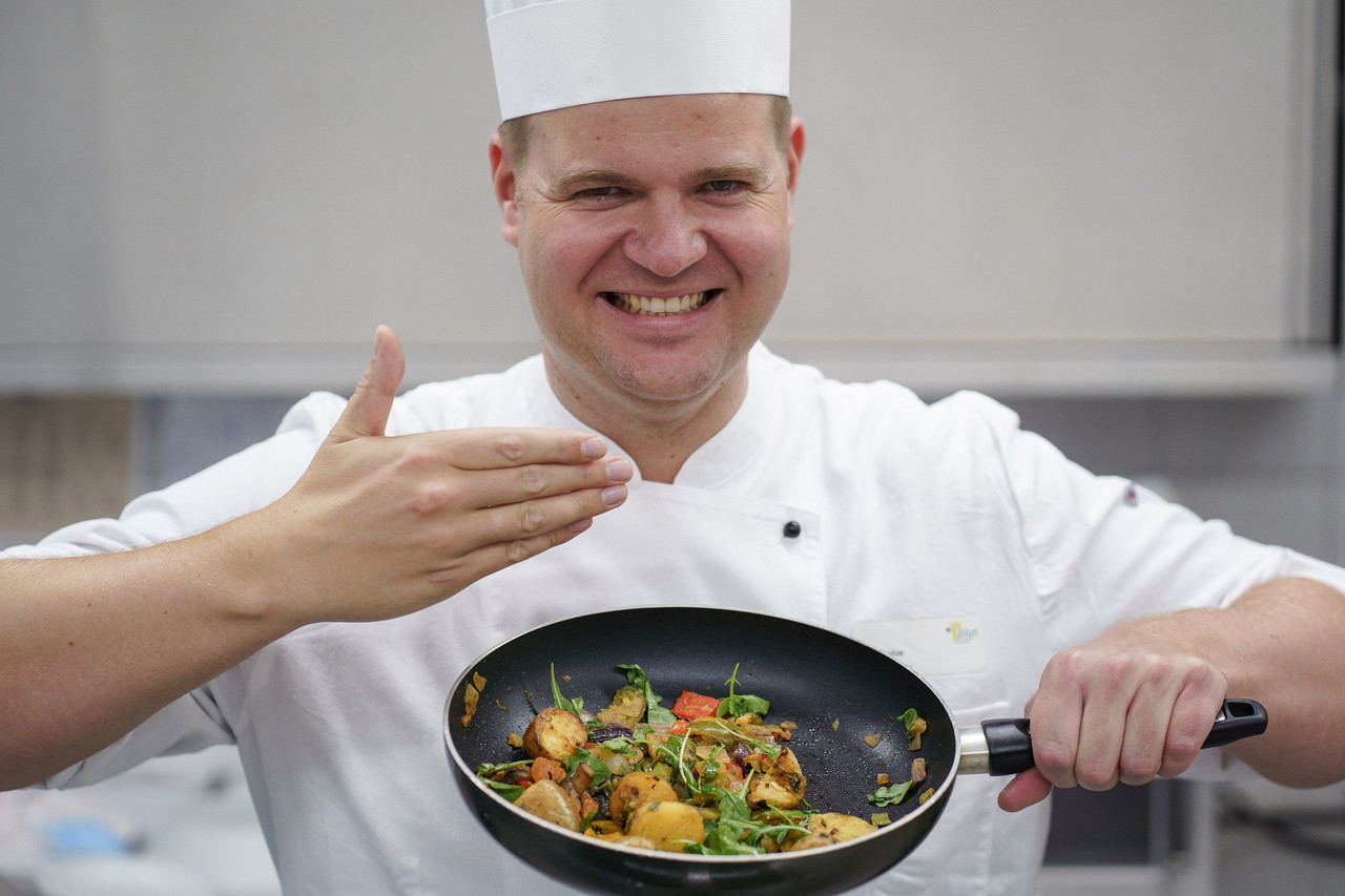 Ein Koch hält eine Pfanne mit lecker duftendem Essen und ist begeistert
