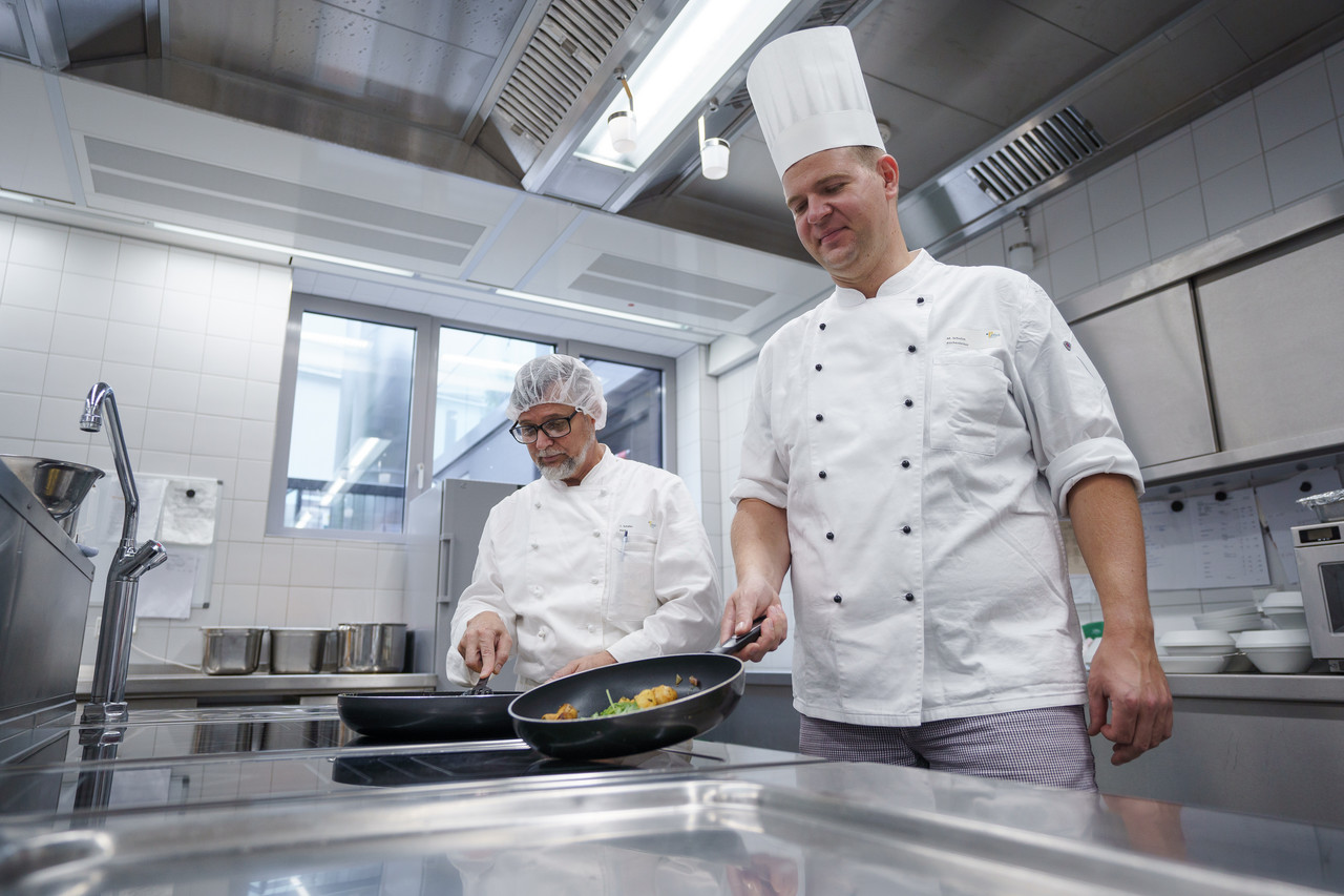 Zwei Köche bereiten am Herd Essen in der Küche des Pius-Hospital zu