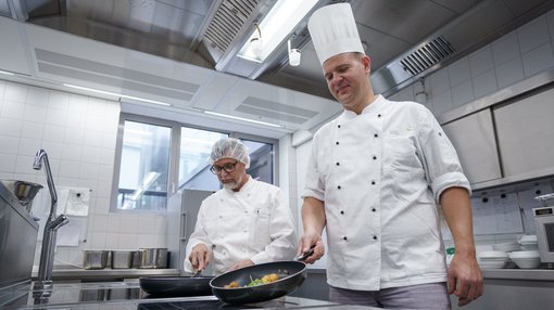Koch und Köche Zwei Köche bereiten am Herd Essen in der Küche des Pius-Hospital zu