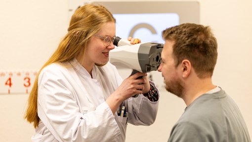 Orthoptik Eine Orthoptistin untersucht einen Patienten mit einem Messgerät